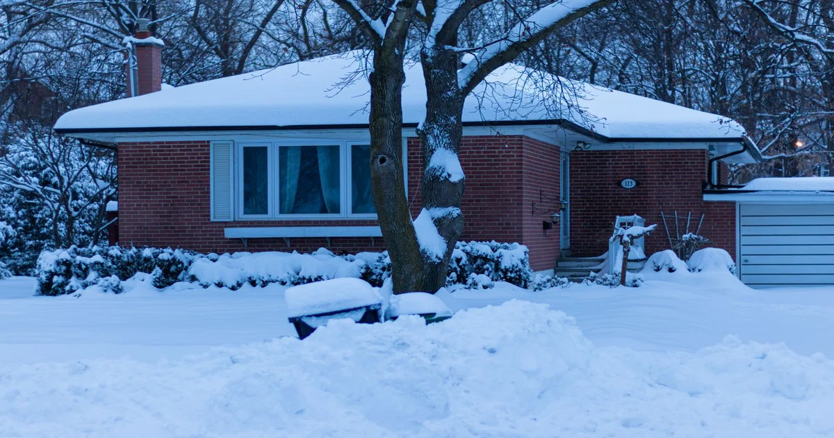 Bungalow de brique au toit en pente couvert de neige après une tempête